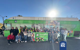 RTC team and friends posing for a picture in front of a bus wrapped with Rosa Park's picture.